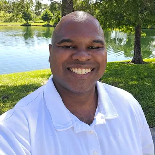Perry Kendrick, author and publisher of PK Publishing, smiling in a white polo by a lake